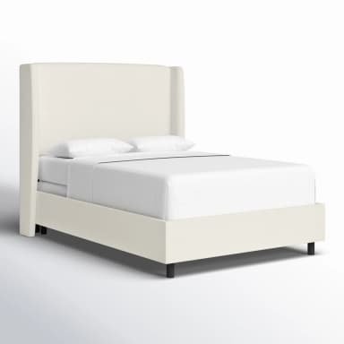 A white upholstered bed frame with a tall, winged headboard. The bed is dressed in white linens, including a duvet and pillows. Dimensions are provided: 55 inches in height for the headboard, 85 inches in length, and 65 inches in width. The frame itself appears to be a platform style with a low profile, indicated by the 4-inch measurement. The legs are black and barely visible. — 3D model