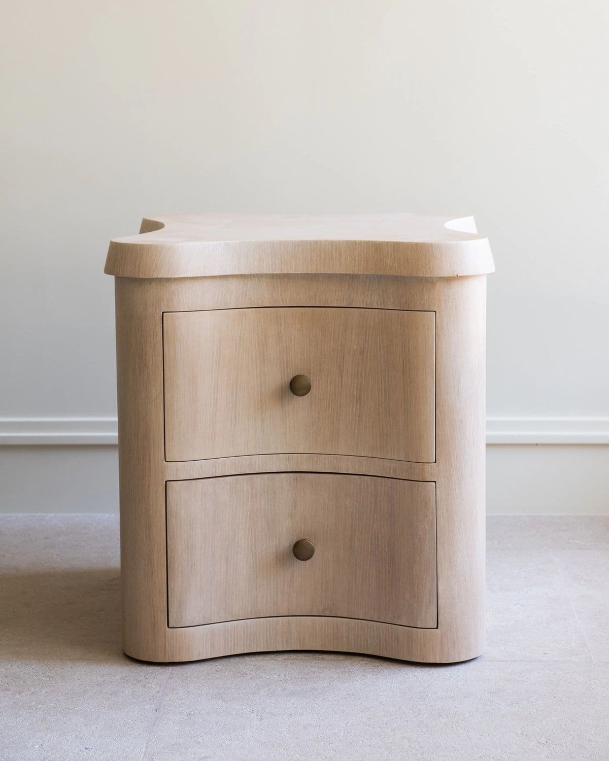 A light-colored wooden cabinet with a distinctive wavy-edged top and two curved drawers, featuring small brass knob pulls. — 3D model