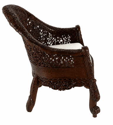 An ornately hand-carved dark wood armchair featuring intricate floral and foliate motifs across its entire frame. The chair has a high, curved backrest and substantial arms, all rendered in deeply carved patterns. It is fitted with a light-colored, possibly cream or off-white, upholstered cushion for the seat. The legs are also carved, ending in scroll-like feet. The overall aesthetic is elaborate and traditional. — 3D model