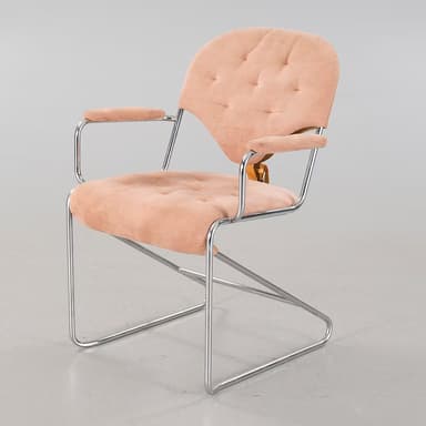 A cantilever armchair with a tubular chrome-plated steel frame. The seat, backrest, and armrests are upholstered in a tufted, salmon-pink, velvety fabric. The backrest has a distinct curved shape and is attached to the frame with leather straps. The armrests are also padded and follow the curvature of the frame. — 3D model