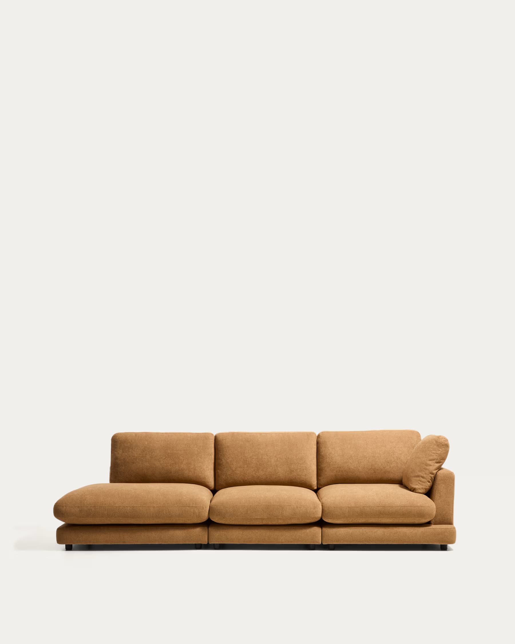 A contemporary, low-profile modular sectional sofa in a warm, textured brown fabric. It consists of three main seating sections, with the leftmost section extending into a deep chaise lounge. The rightmost section has a small, loose back cushion angled for support. The sofa sits on discreet, recessed dark feet. The design emphasizes comfort with generously padded, rounded cushions and a relaxed aesthetic. — 3D model