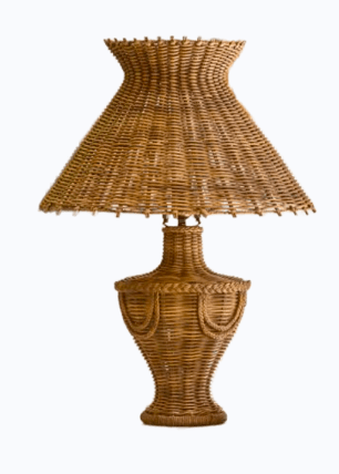 A table lamp constructed entirely from woven natural fibers, possibly rattan or wicker. The lamp features a wide, flared lampshade with a slightly flared top, supported by a pedestal base. The base has a classic urn shape with decorative woven elements resembling draped fabric on its widest section. The weaving technique is visible throughout, creating a textured and organic aesthetic. — 3D model