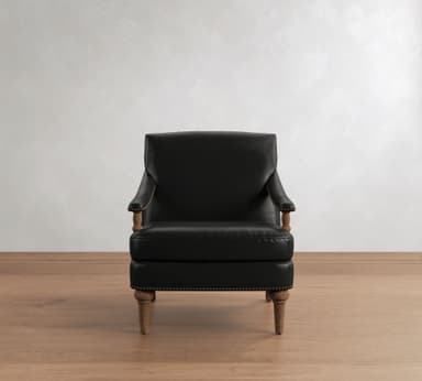A traditional style armchair upholstered in black leather, featuring prominent brass nailhead trim along the armrests and base. The chair is supported by turned wooden legs and has exposed wooden arm supports, contributing to its classic aesthetic. — 3D model