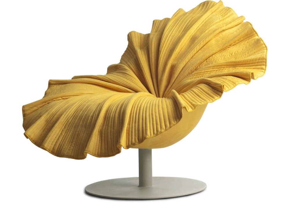 A highly distinctive contemporary swivel lounge chair, featuring a unique, biomorphic form that resembles an unfurling flower petal. The chair is upholstered in a rich, textured yellow fabric, deeply pleated and gathered to create a voluminous, sculptural back and seat. It rests on a minimalist, gray-finished metal swivel pedestal base with a circular foot. The design emphasizes organic shapes and a bold, artistic aesthetic, making it a prominent accent piece. — 3D model