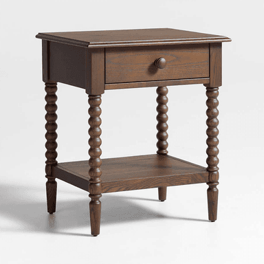 A dark brown wooden nightstand featuring a single top drawer with a round wooden pull knob and an open lower storage shelf. The table is supported by four distinctive bobbin-turned legs, which taper slightly at the bottom. The wood exhibits a visible grain pattern, suggesting a solid wood construction with a rich, dark stain. — 3D model