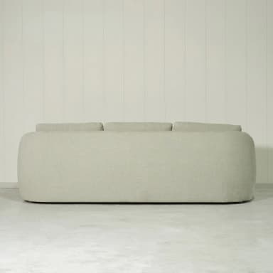 A three-seater sofa with a curved armrest on the left side. The sofa has a tailored base and three seat cushions. The back features three distinct cushions, all upholstered in a light-colored, textured fabric. — 3D model