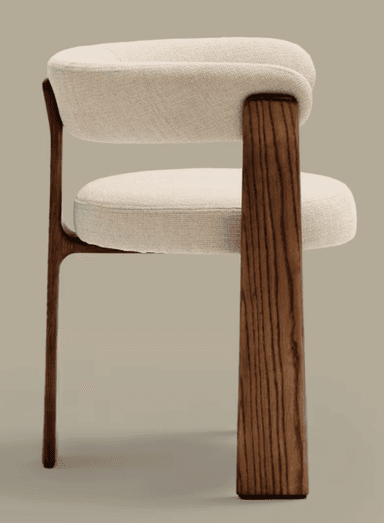 A modern armchair with a curved upholstered backrest and seat, supported by four solid wood legs. The legs have a distinct organic shape and visible wood grain. The upholstery is a textured, light-colored fabric. The design is minimalist and contemporary. — 3D model
