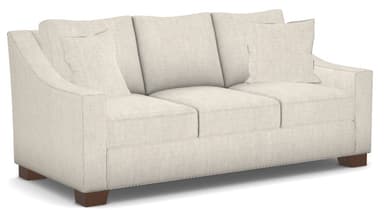 A contemporary three-seater sofa, upholstered in a light-colored, textured fabric, likely off-white or cream. It features broad track arms, three separate seat cushions, and three loose back cushions, along with two smaller accent pillows. The sofa rests on low, rectangular dark wood block feet. — 3D model