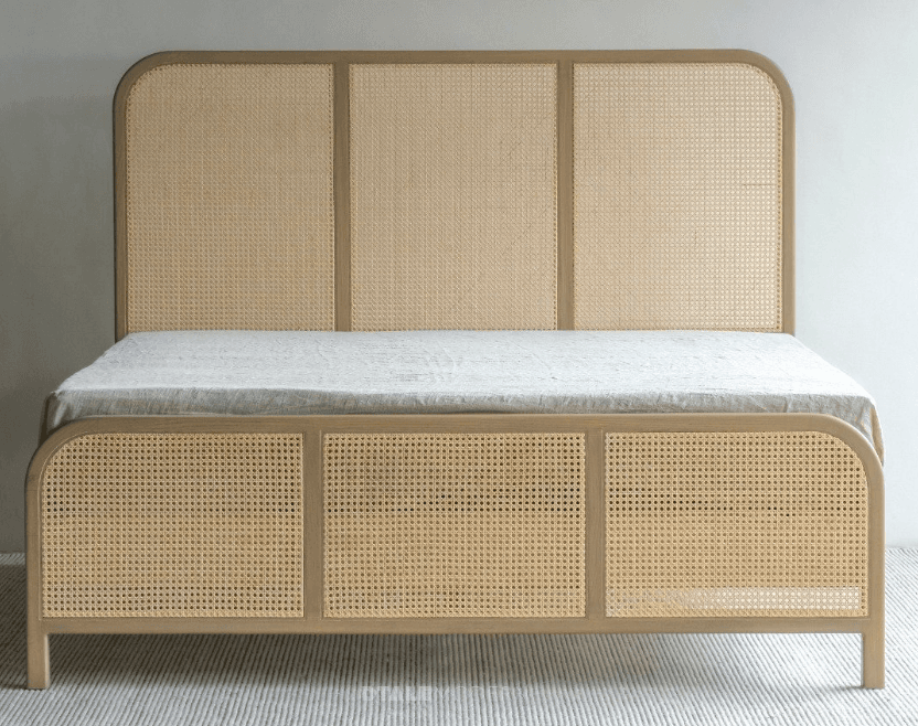 A modern platform bed frame featuring a light-toned wooden structure with cane webbing inserts on both the headboard and footboard. The design incorporates gently rounded edges for a soft, contemporary aesthetic. A plain white mattress is visible on the platform. — 3D model