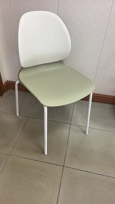 A modern side chair with a molded shell seat and back. The seat and back appear to be made of a smooth, durable plastic or composite material. The shell has a distinct organic, curved shape, with the back extending upwards and curving slightly inwards. The chair is supported by thin, tapered metal legs that are white in color and arranged in a sled-like base configuration. The overall aesthetic is minimalist and contemporary. — 3D model