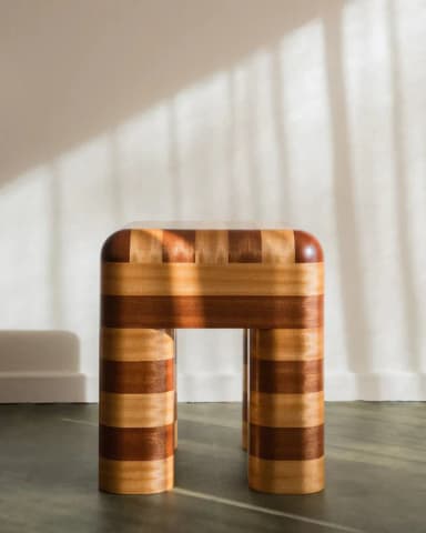 A small, four-legged stool with a striped pattern created by alternating wood tones. The top surface is rounded and the legs are cylindrical with rounded edges. The contrasting wood grain suggests a visually striking design. — 3D model
