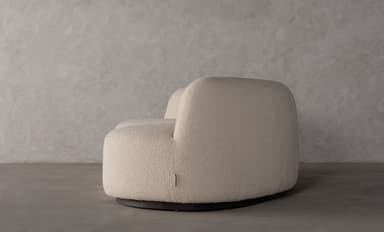 A contemporary curved sofa with a textured upholstery and a flowing, organic shape. The sofa features a single continuous seat and backrest, with no visible arms. The silhouette is sleek and modern, designed to fit within a variety of interior design schemes. — 3D model