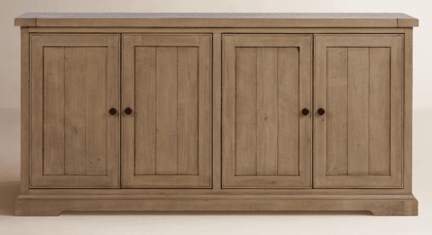 A wooden sideboard featuring four cabinet doors arranged in two symmetrical pairs. Each door has a vertical plank design within a recessed panel and is fitted with a small, round, black knob. The top surface appears to be a distinct piece with a slight overhang. The base of the unit has a subtle, molded plinth. — 3D model