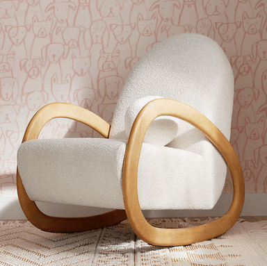 A contemporary rocking chair featuring a plush, off-white boucle upholstered seat and back, supported by a distinctive curved light wood frame that also forms the armrests and rocking base. The design emphasizes organic shapes and a seamless integration of materials. — 3D model
