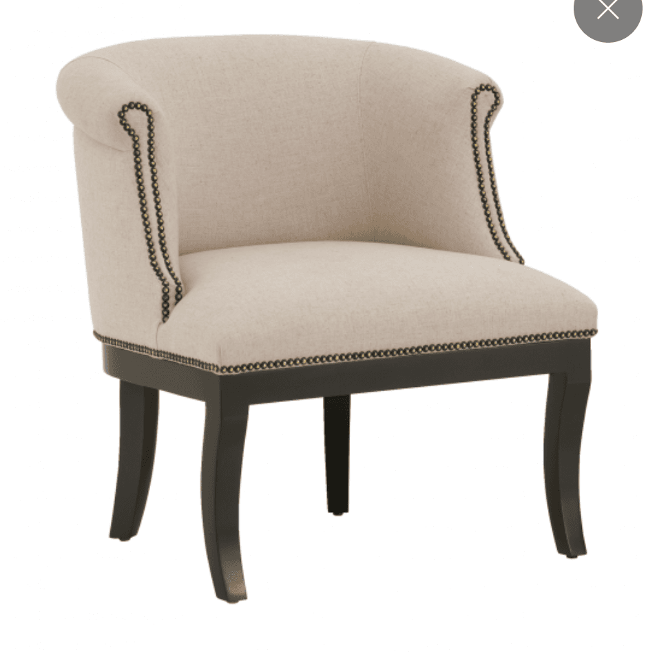 An upholstered barrel back armchair featuring a light-colored fabric, dark wood legs, and decorative metal nailhead trim along the armrests and base. The chair's back and armrests form a continuous, curved shape, offering a compact yet comfortable seating option. — 3D model