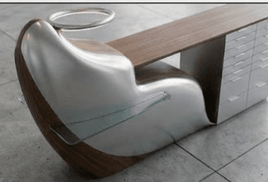 A highly modern and sculptural desk unit featuring an integrated ergonomic chair, a work surface, and a multi-drawer storage cabinet. The design combines a curved, polished metal shell with dark wood accents and a glass side shelf. An illuminated ring fixture is positioned above the chair. — 3D model