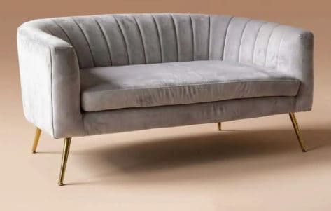 A light grey upholstered loveseat featuring a channel-tufted backrest and rounded arms. The piece is supported by four slender, angled gold-finished metal legs, giving it a modern and elegant appearance. The seating area consists of a single, continuous cushion. — 3D model