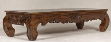 A low-profile rectangular table crafted from dark wood, featuring extensively carved details along its apron and legs. — 3D model