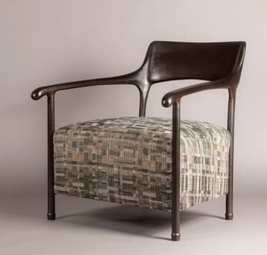 A modern armchair featuring a dark, sculptural wooden frame that forms the armrests, backrest, and legs. The armrests curve gracefully, extending from the backrest and supported by a leg structure. The seat is upholstered in a textured fabric with a multi-tonal geometric pattern in shades of beige, grey, and subtle orange. The chair presents a contemporary aesthetic with clean lines and organic shapes. — 3D model