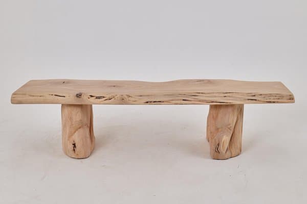A rustic coffee table constructed from natural wood elements. The tabletop is a single slab with a live edge, showcasing the natural contours and grain of the wood. It is supported by two solid, irregularly shaped wooden block legs that mimic the organic form of tree trunks. The overall design emphasizes natural forms and textures. — 3D model