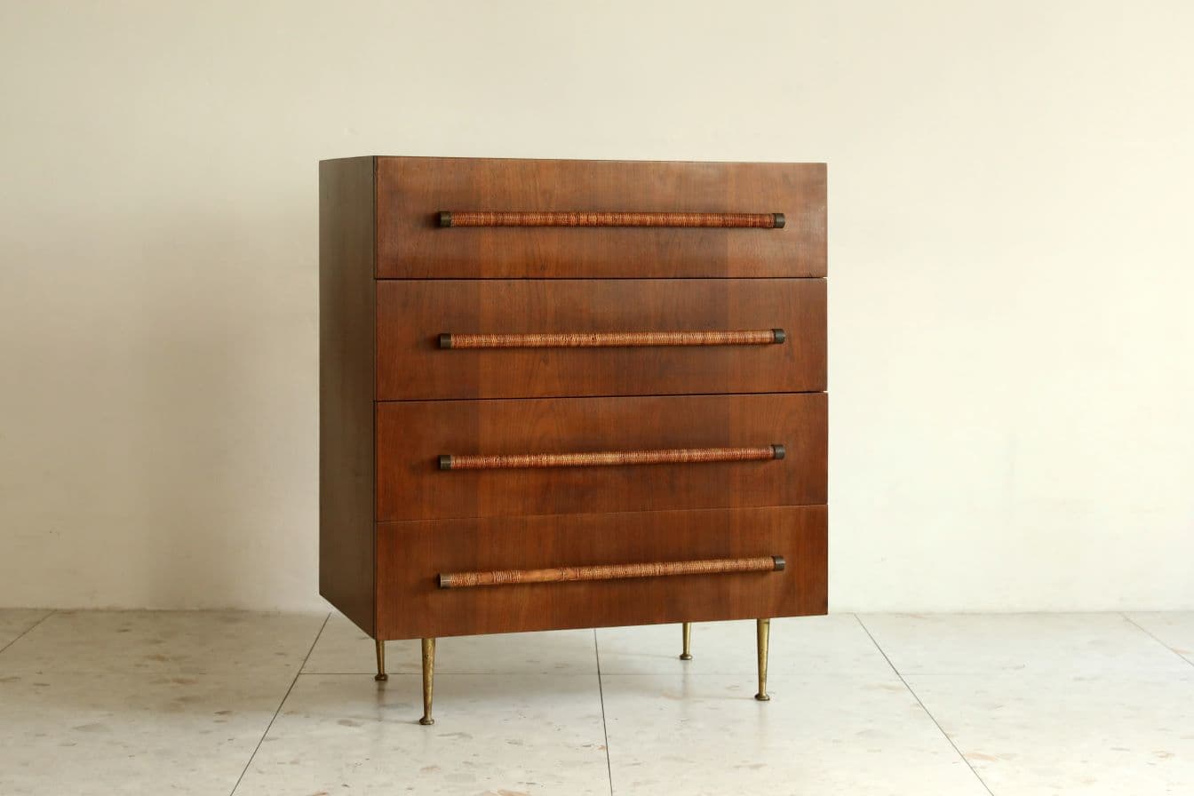 A Mid-Century Modern four-drawer chest with a warm wooden finish, rattan-wrapped brass pulls, and tapered brass legs. — 3D model