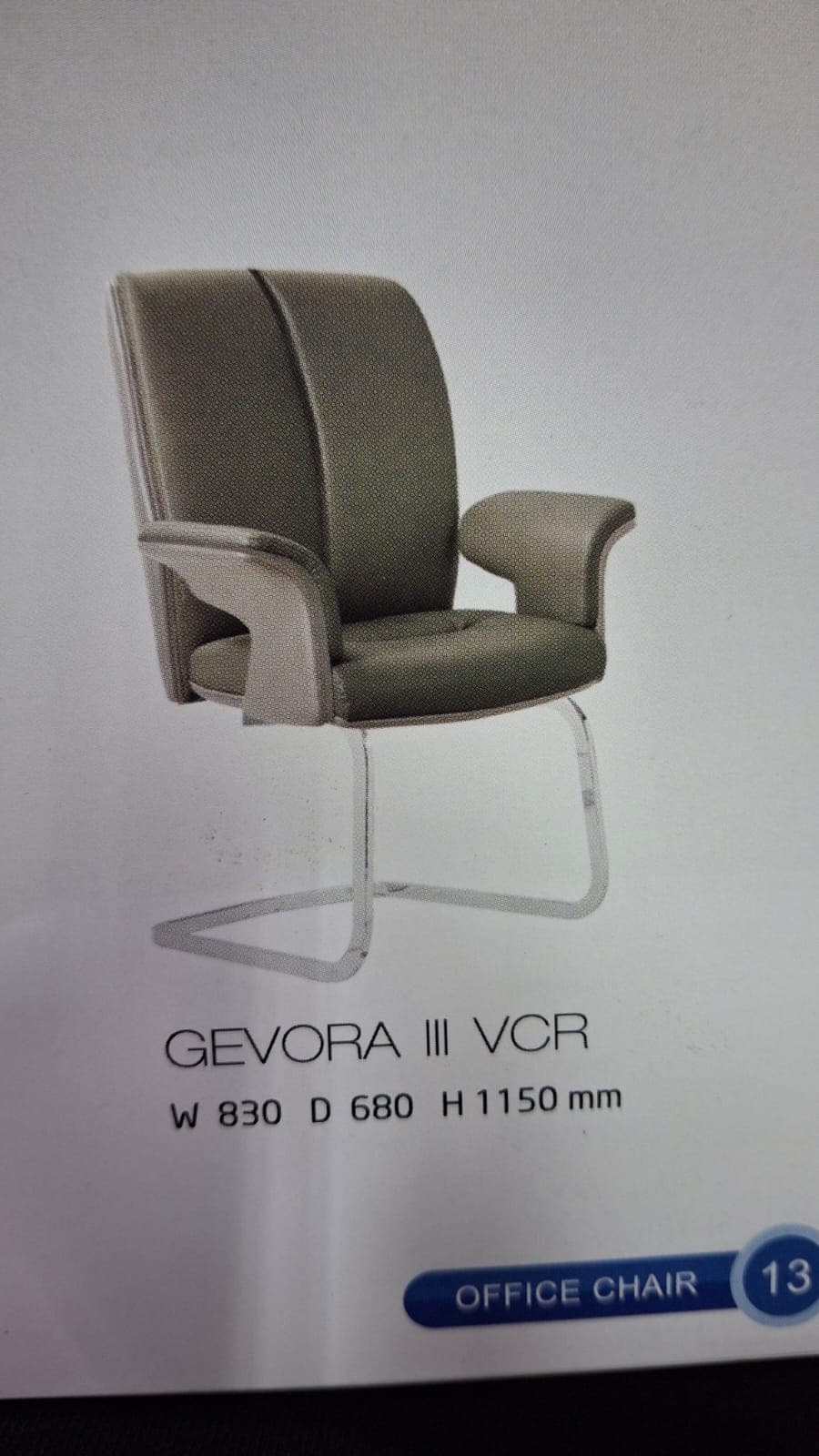 A modern office armchair featuring a padded seat and backrest upholstered in a neutral grey material. The backrest has two subtle vertical sections, and the armrests are integrated, also with padded tops. The chair sits on a distinctive polished silver-colored metal cantilever base, forming a sled-like frame that extends from the armrests. — 3D model