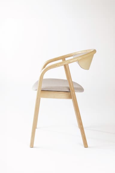 A modern armchair constructed with a light-toned wooden frame and upholstered seat and backrest. The frame features smoothly curved armrests and back support. The design is minimalist and contemporary, with slender, tapered legs. — 3D model