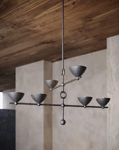 A six-light chandelier featuring a linear, branching design with a distressed bronze finish. The fixture hangs from a ceiling canopy via a single downrod. Its central vertical stem branches into two horizontal arms, with the upper arm supporting two light sources and the lower, longer arm supporting four. Each light source is housed within a small, bowl-shaped shade, pointing upwards. Circular accents are integrated into the central stem where the arms attach. The metal surface has a textured, aged appearance. — 3D model