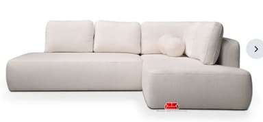 A modern, off-white L-shaped sectional sofa with soft, rounded edges and a low profile. It features plush seat and back cushions, and two spherical accent pillows. The fabric appears textured, possibly bouclé. — 3D model