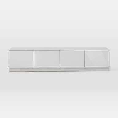A sleek, modern media console with a low-profile design, featuring four equally sized, handle-less doors for storage. The unit is finished in a light gray or off-white hue, with the doors appearing to have a glossy or lacquered finish, contrasting with a potentially matte finish on the top surface and base. It rests on a discreet plinth base, contributing to its minimalist aesthetic. The clean lines and flush-fitting doors emphasize contemporary design. — 3D model