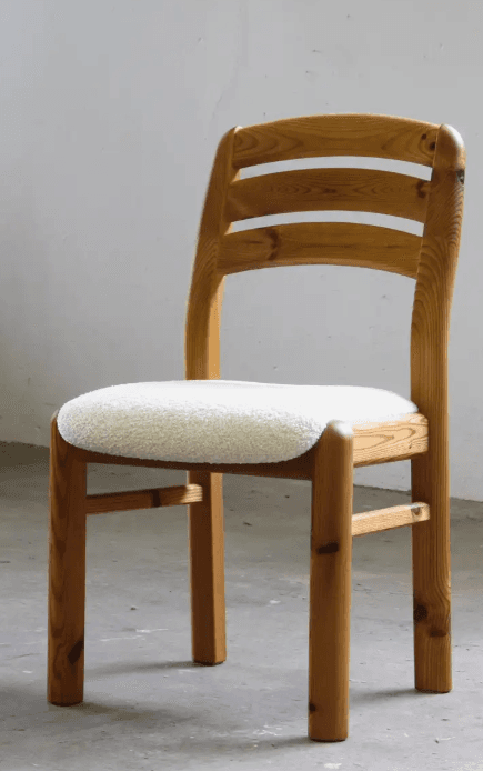 A wooden chair with a light-colored, textured seat cushion. The chair has a slatted backrest and rounded legs. The wood appears to be pine, showing natural grain and knots. — 3D model