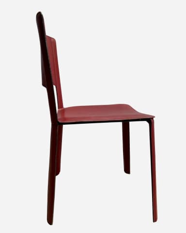 A modern, armless chair with a minimalist design. The seat and backrest are upholstered in a continuous piece of material that wraps around the frame. The chair features a cutout in the backrest for a modern aesthetic. The legs are straight and integral to the overall structure. Visible stitching around the edges of the seat and backrest indicates careful construction. — 3D model