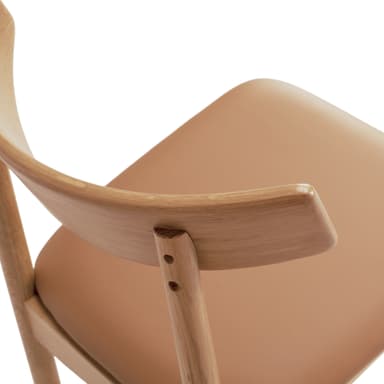 A modern bar stool featuring a light oak wood frame, a gently curved backrest, and a tan leatherette padded seat. It is designed with integrated footrests and straight, round tapered legs. — 3D model