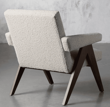 A mid-century modern style lounge chair featuring a light-toned, textured bouclé upholstery and dark-stained angular wooden legs. The chair has wide, flat armrests and a gently reclined backrest, designed for comfort and aesthetic appeal. The exposed wooden frame provides a strong visual structure. — 3D model