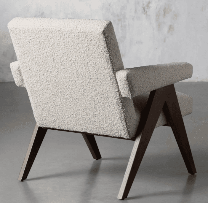 A mid-century modern style lounge chair featuring a light-toned, textured bouclé upholstery and dark-stained angular wooden legs. The chair has wide, flat armrests and a gently reclined backrest, designed for comfort and aesthetic appeal. The exposed wooden frame provides a strong visual structure. — 3D model