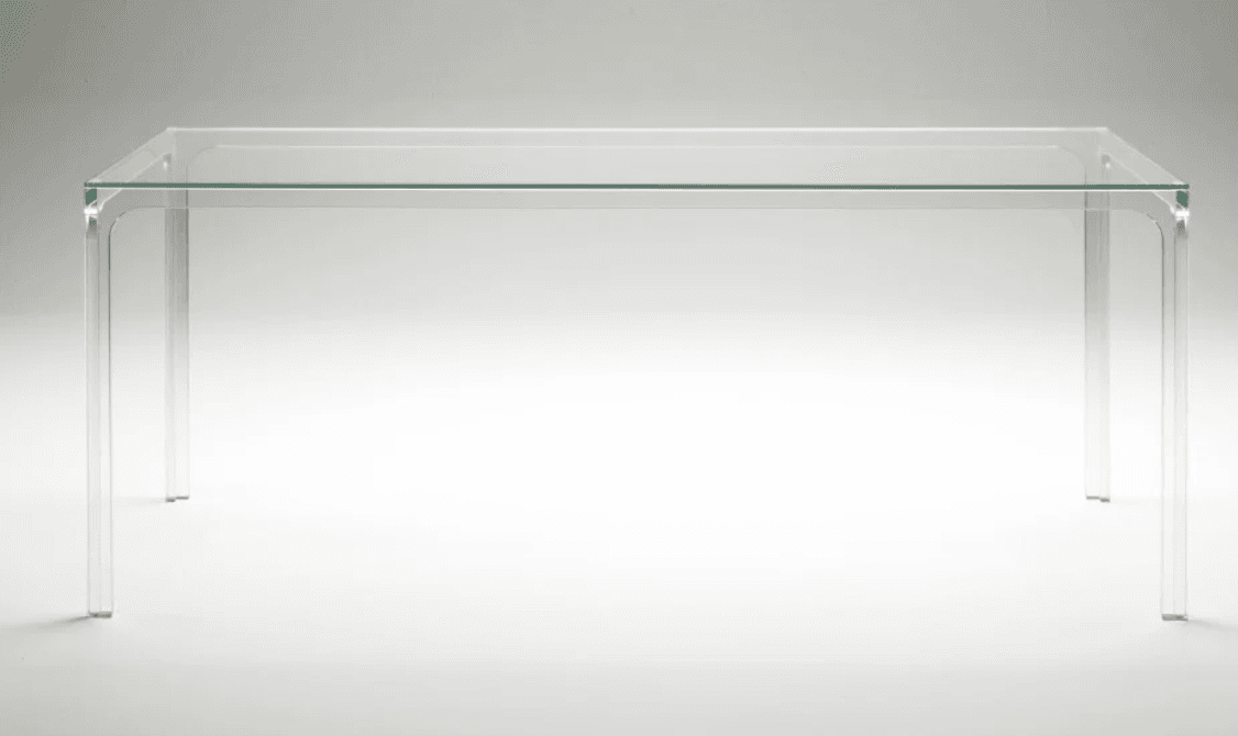 A modern rectangular table constructed entirely from clear, transparent material, likely glass or acrylic. It features a flat tabletop and four integrated legs, with smooth, rounded curves at the corners where the top transitions into the legs. The design is minimalist and visually light. — 3D model