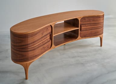 A contemporary media console crafted from walnut wood, featuring a long, low profile with two enclosed compartments and a central open shelving unit. The doors are sliding, with distinctive reeded details on their curved ends and prominent wood grain. The entire piece is supported by elegant, tapered legs. — 3D model