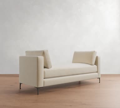 A contemporary upholstered daybed with integrated armrests at both ends, featuring a flat seating surface and two loose bolster cushions for back support, all resting on slender metal legs. — 3D model