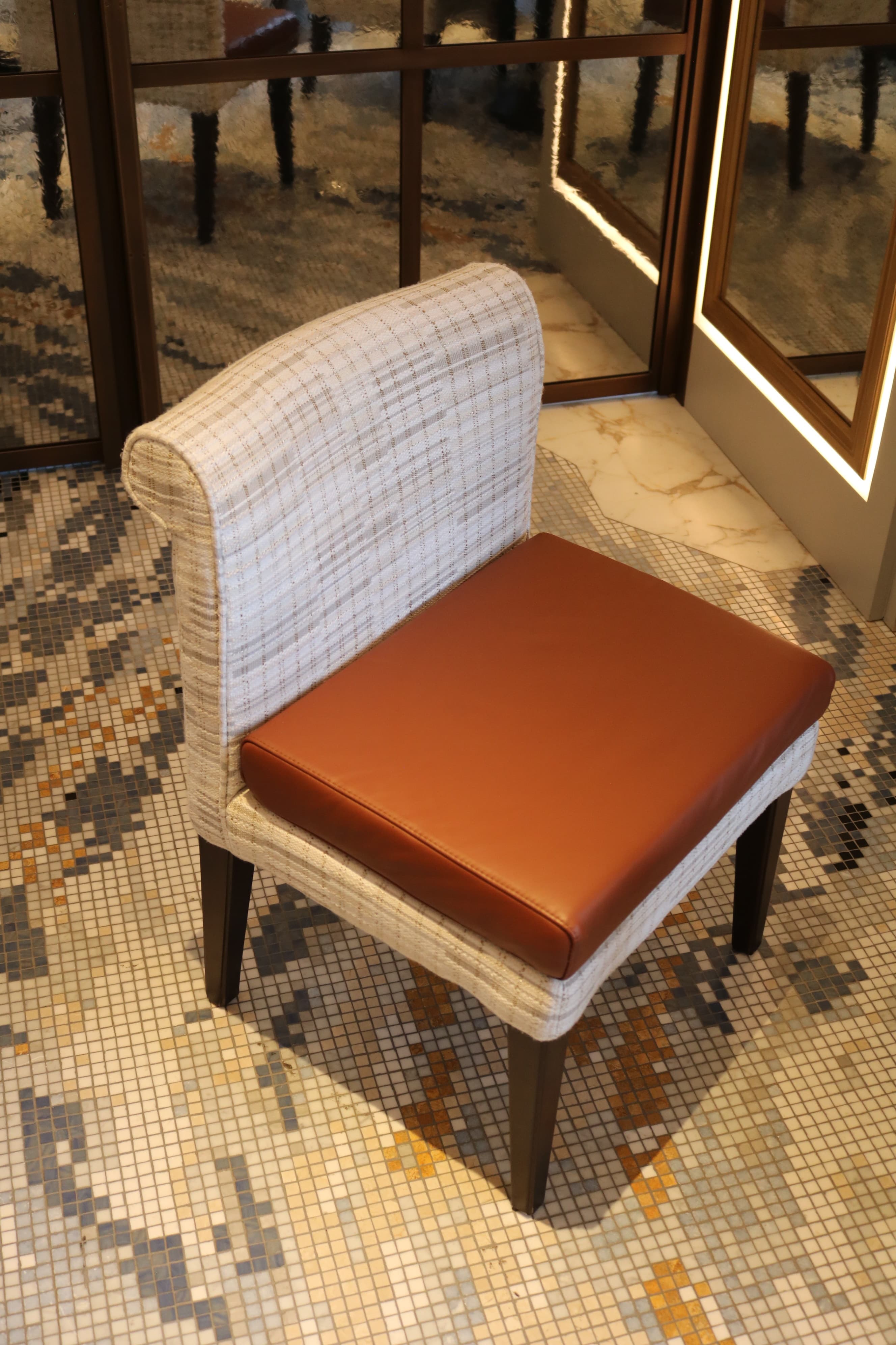 An armless dining chair featuring a light, patterned fabric upholstered back and frame, contrasted with a smooth, warm brown leather seat cushion. The chair stands on four dark, slightly tapered wooden legs. — 3D model