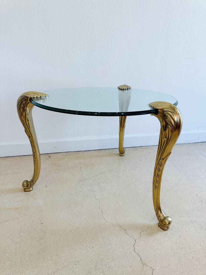 A round accent table featuring a clear glass top supported by three ornate, gilded metal legs designed in a Rococo Revival style. — 3D model