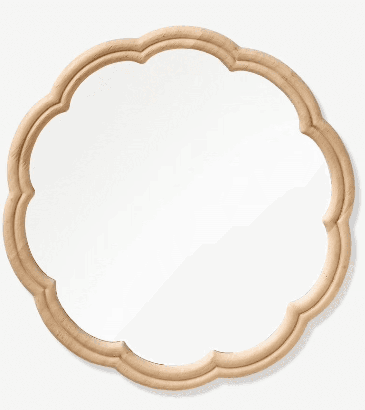 A decorative wall mirror featuring a distinct scalloped frame made from natural, light-toned wood. The mirror's shape is generally circular, accented by the undulating, carved edges of its frame. — 3D model