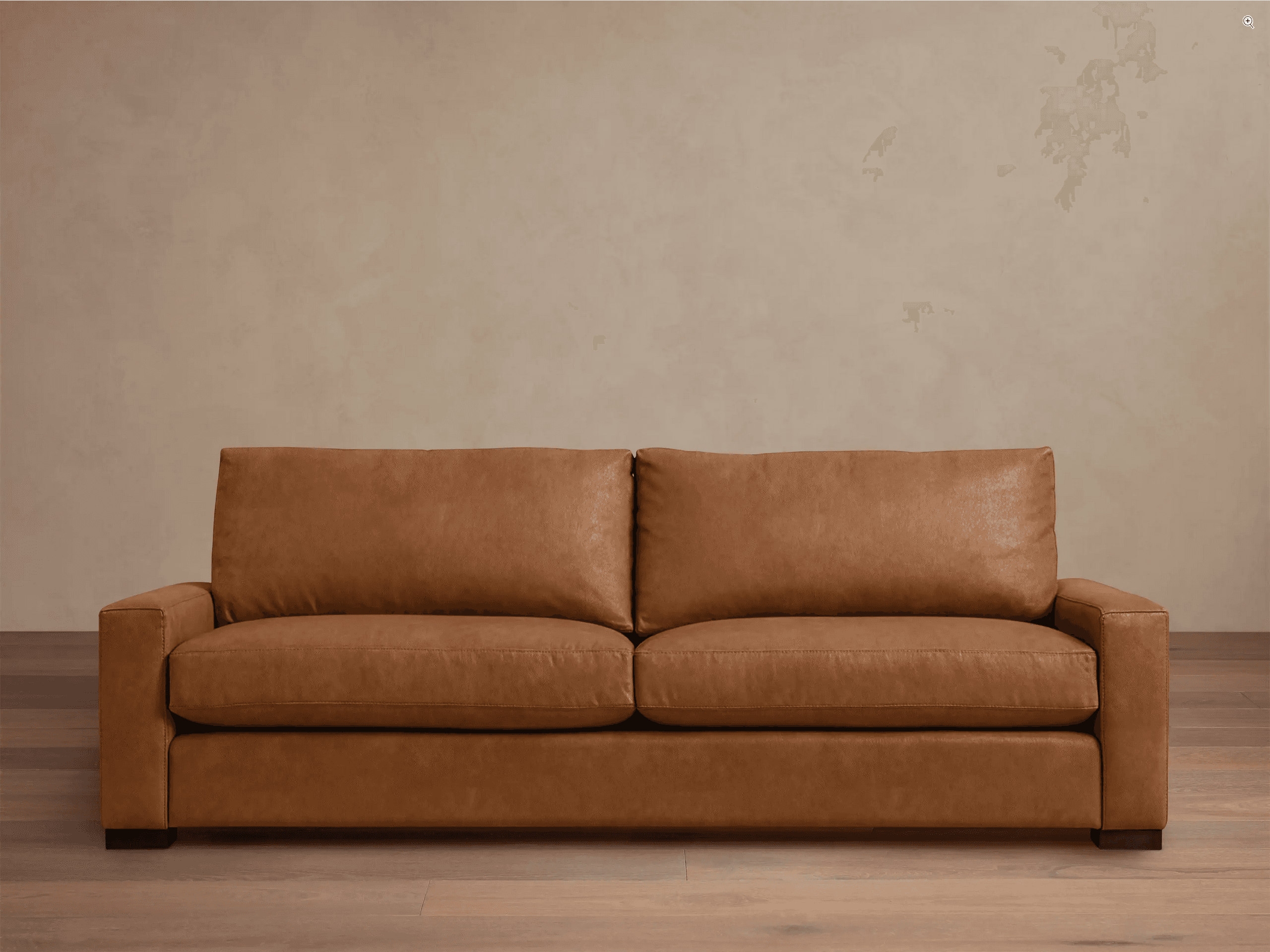 A contemporary two-seater sofa upholstered in a warm, light brown (cognac) leather, featuring clean lines, track arms, and two generously sized seat cushions and two back cushions. It sits on short, dark, recessed block feet. — 3D model
