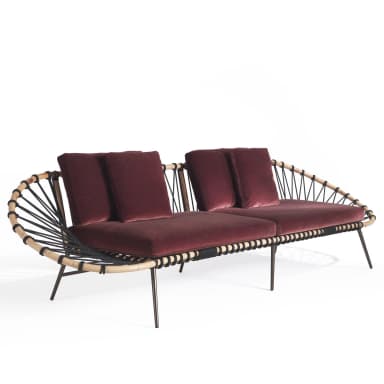 A contemporary sofa featuring a distinctive design with a woven backrest and armrest on one side, and a more open structure on the other. The seating and back cushions are upholstered in a deep red velvet fabric. The frame appears to be constructed from wood or a wood-like material, with thin metal legs. The backrest is formed by a curved structure with interwoven black cords or ropes. — 3D model