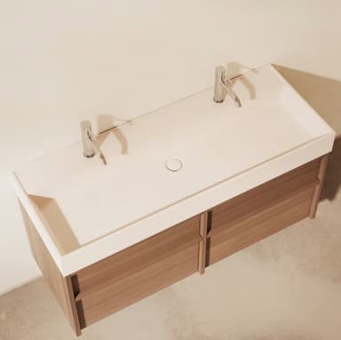 A modern wall-mounted double bathroom vanity featuring a light wood-grain cabinet, a white integrated countertop with two sinks, and two contemporary brushed metal single-handle faucets. The cabinet has four drawers arranged in two columns, each appearing handleless for a sleek aesthetic. — 3D model