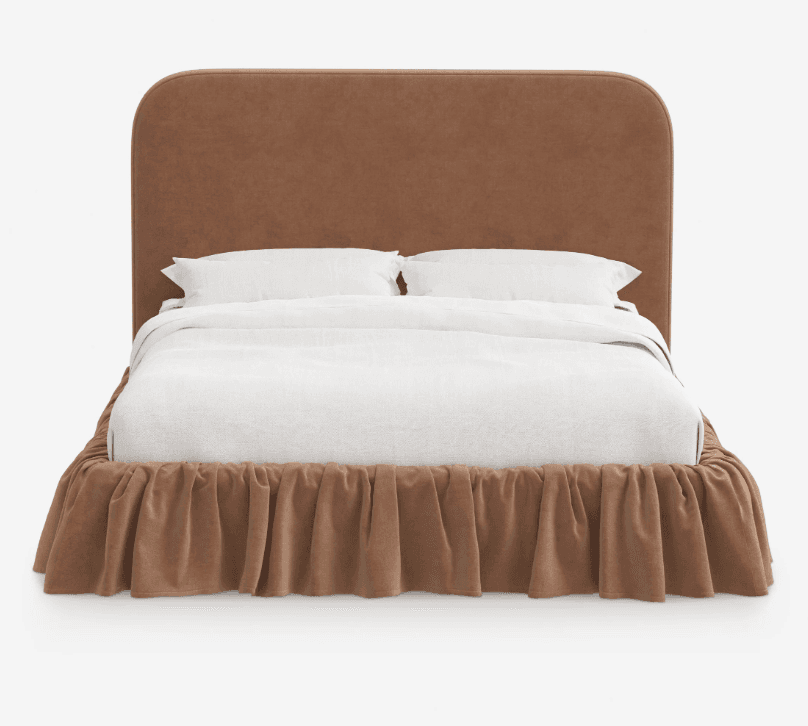 A fully upholstered bed frame featuring a soft brown/taupe fabric, a generously padded headboard with smoothly rounded corners, and a matching ruffled bed skirt that conceals the frame. The bed is presented with clean white bedding, including a duvet and two pillows, creating a plush and inviting appearance. The design emphasizes comfort and a cohesive, soft aesthetic. — 3D model
