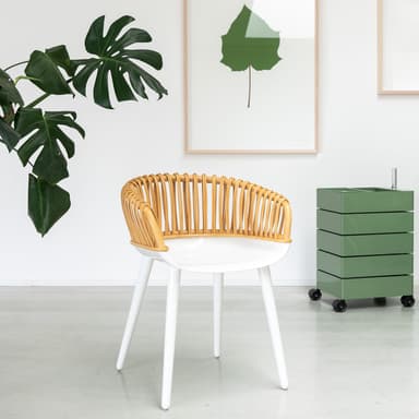 A modern accent chair featuring a curved, slatted rattan backrest and integrated armrests, a smooth white molded seat, and four splayed white legs. — 3D model