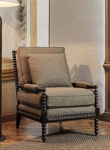 A dark-stained wooden armchair with a distinctive bobbin-turned frame and light brown upholstered cushions, accented with decorative nailhead trim. — 3D model