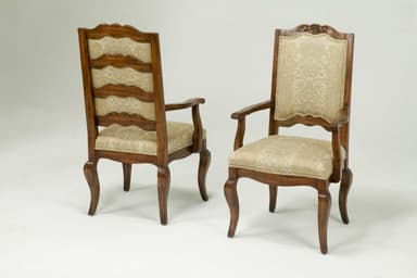 A traditional armchair featuring a dark, carved wooden frame and upholstered seat and backrest in a light-colored, patterned fabric. The chair exhibits cabriole legs and ornate detailing, particularly on the crest rail of the back. — 3D model