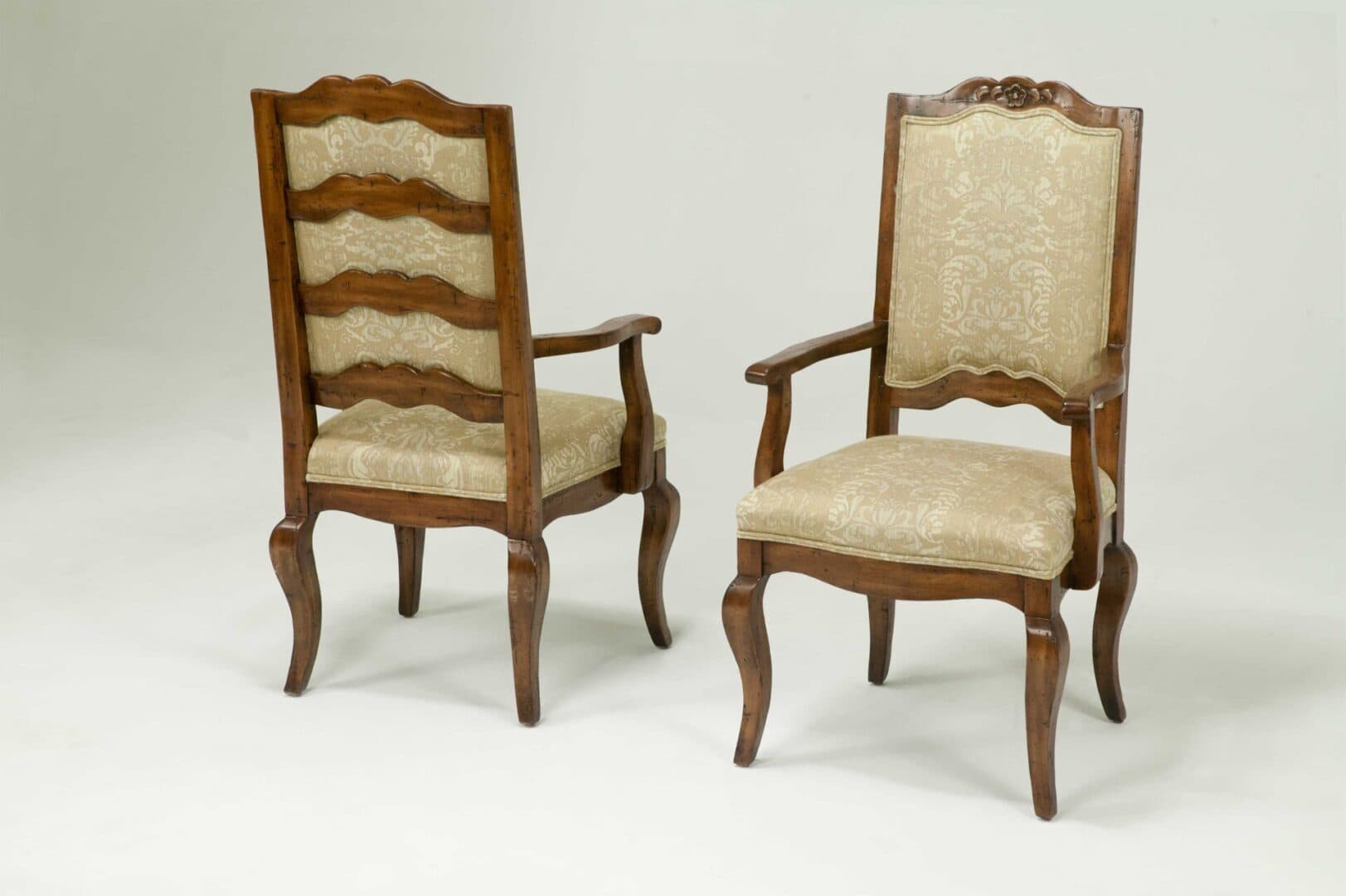 A traditional armchair featuring a dark, carved wooden frame and upholstered seat and backrest in a light-colored, patterned fabric. The chair exhibits cabriole legs and ornate detailing, particularly on the crest rail of the back. — 3D model