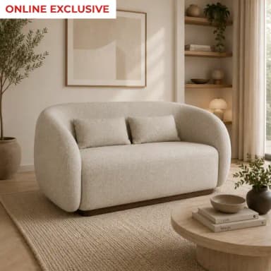 A contemporary two-seater loveseat featuring a distinct curvilinear silhouette with seamlessly rounded arms and backrest, upholstered in a light beige, textured bouclé fabric. The piece sits on a recessed, dark wooden plinth base, creating a floating effect. It includes two rectangular throw pillows matching the upholstery. — 3D model